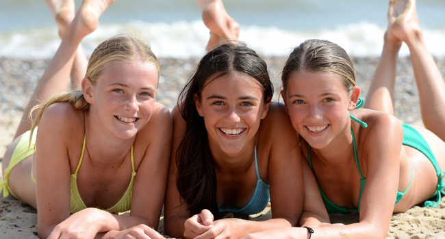 Schülerinnen am Strand in Exmouth während einer LISA! Sprachreise liegen im Sand und genießen Sonne und Meer