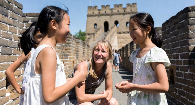 Bildungsurlaub China mit LISA! – Chinesisch lernen, Kultur und authentische Erlebnisse Erwachsene im Gespräch mit Kindern auf der Chinesischen Mauer während eines LISA! Bildungsurlaubs erleben Kultur und lernen Chinesisch