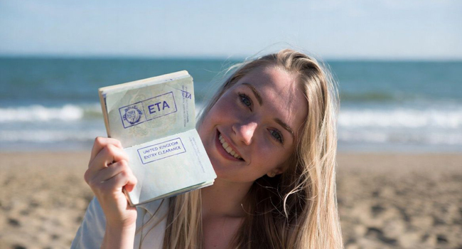 Frau am Strand zeigt Reisepass mit ETA Einreisegenehmigung während einer LISA! Sprachreise nach England