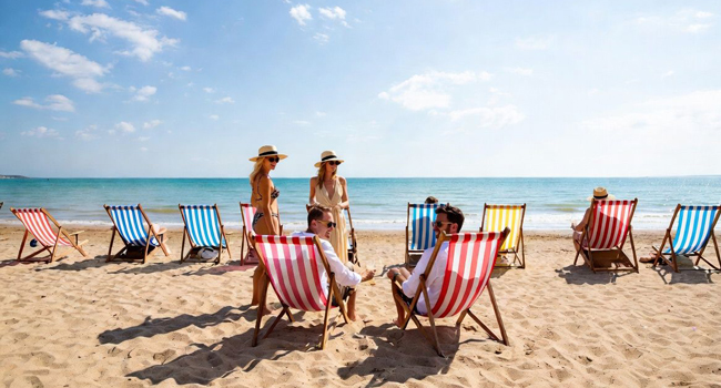 Erwachsene Teilnehmer entspannen am Strand in Bournemouth auf Liegestühlen während einer LISA! Sprachreise in England