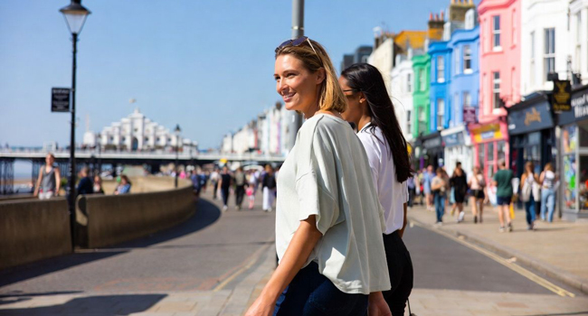 Teilnehmerinnen auf der Promenade in Brighton mit bunten Häusern während einer LISA! Sprachreise in England