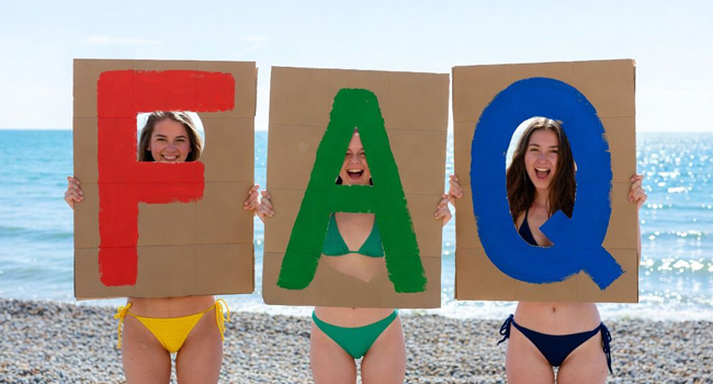 Drei Teilnehmerinnen am Strand in Brighton halten FAQ-Schilder während einer LISA! Sprachreise in England