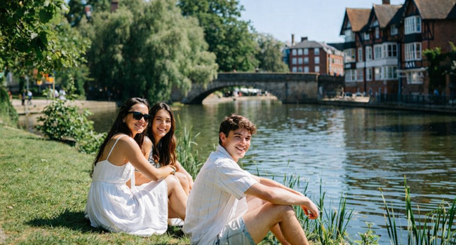 Erwachsene Teilnehmer einer LISA! Sprachreise in Cambridge City England sitzen am Fluss und genießen Sonne und Freizeit