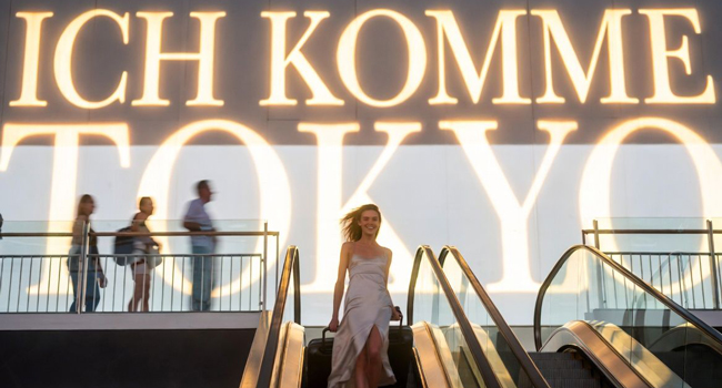 Ankunft in Tokio während einer LISA! Sprachreise Frau mit Koffer auf Rolltreppe startet ihr Sprachabenteuer in Japan