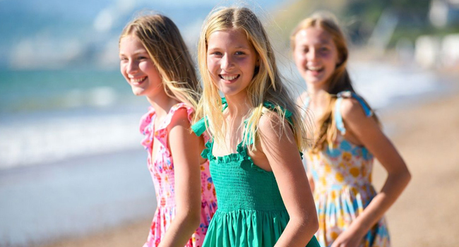 Drei Schülerinnen am Strand in Bournemouth England während einer LISA! Sprachreise tragen Sommerkleider und genießen das Meer