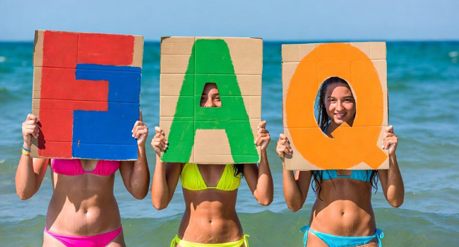 Schülerinnen am Strand in Exmouth halten FAQ Buchstaben während einer LISA! Sprachreise mit Meer im Hintergrund