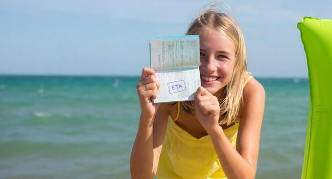  Schülerin am Strand in Ilfracombe während einer LISA! Sprachreise zeigt Reisepass und ETA Einreisedokument für England