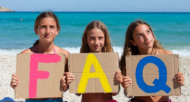 Schülerinnen auf Jersey halten FAQ Buchstaben am Strand während einer LISA! Sprachreise mit Meer im Hintergrund