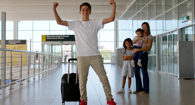 Ankunft Schüler in Malta zur Sprachreise mit erhobenen Armen zur Siegerpose mit Gasteltern im Hintergrund