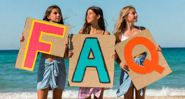 Drei Schülerinnen am Strand in Antibes Frankreich halten FAQ Schilder während einer LISA! Sprachreise