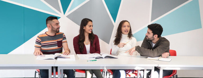 Vier Schüler sitzen im Klassenzimmer und diskutieren bei einem Sprachkurs Englisch