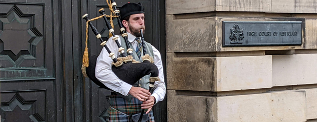 Ein Dudelsackspieler steht vor einem Gebäude in Edinburgh und spielt