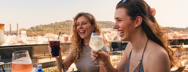 Zwei Frauen sitzen auf einer Terrasse in Barcelona und trinken kühle Getränke