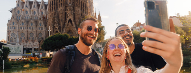 Drei Erwachsene machen ein Selfie vor der Kathedrale von Barcelona