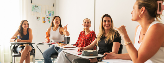 Fünf Damen sitzen im Klassenzimmer und reden vergnügt beim Bildungsurlaub in Barcelona
