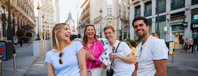 Vier Erwachsene spazieren mit Freude durch Madrid beim Bildungsurlaub