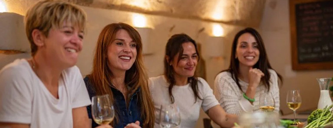 Freizeit und Wein beim Bildungsurlaub Spanisch auf Mallorca Vier damen sitzen gemeinsam beim Essen und probieren Wein