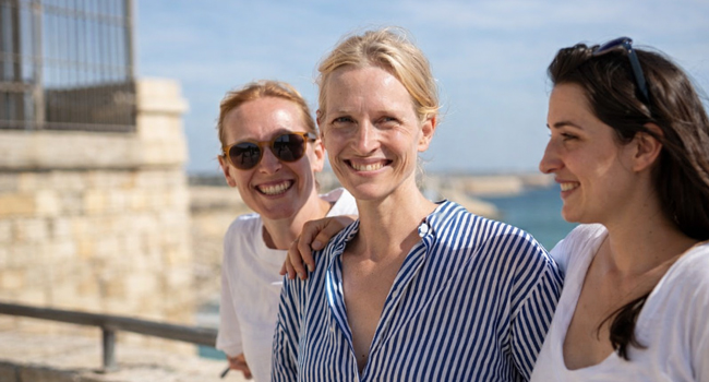 Drei Frauen stehen zusammen an einer Brüstung vor dem Meer bei einem Bildungsurlaub