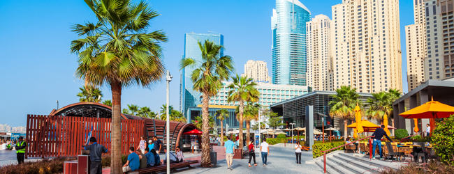 Spaziergang beim Jumeirah Beach bei einem Bildungsurlaub in Dubai Jumeirah Beach in Dubai mit Menschen, Cafes und Hochhäusern im Hintergrund