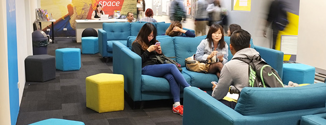 Schüler in der Sprachschule in Sydney sitzen in der Lounge auf blauen Sofas