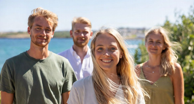 2 blonde Frauen und 2 Männer aus Deutschland auf Sprachreise in Malta mit Meer im Hintergrund und Sonne im Haar