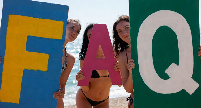 Frauen am Strand mit großen FAQ-Buchstaben für Fragen und Antworten zu Sprachreisen in Antibes mit LISA! Sprachreisen