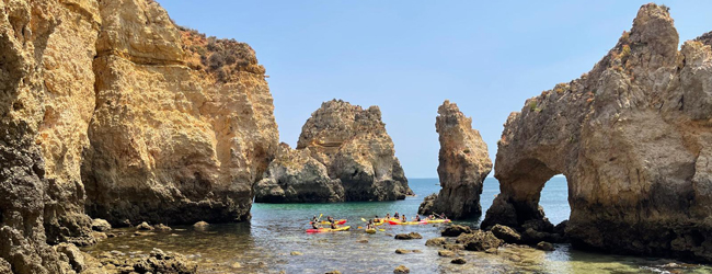 Ausflug mit dem Paddelboot bei einer Portugiesisch-Sprachreise in Faro Zwischen Felsen im Meer paddeln Boote hindurch bei einer Sprachreise in Faro