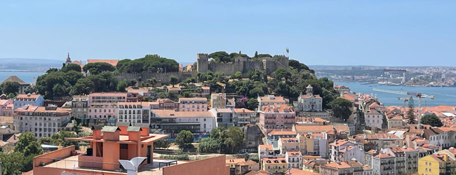 Hügel mit Gebäuden und Blick auf das Meer bei einer Sprachreise in Lissabon