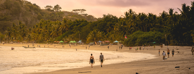 Bucht in Sámara mit Wellen, Spaziergängern und Palmen am Abend