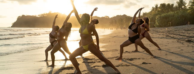 Yoga am Strand am Morgen in Costa Rica Mehrere Frauen in Bikini machen am Morgen am Strand Yogaübungen