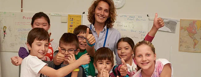 Fröhlicher Unterricht von Kindern bei einer Sprachreise für Familien Eine fröhliche Gruppe von Kindern mit ihrem Lehrer im Klassenzimmer bei einer LISA! Sprachreise für Familien