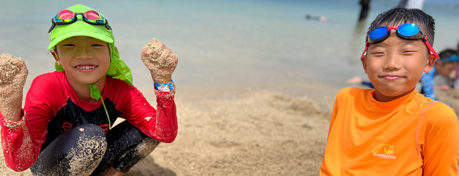 Zwei Jungen spielen im Sand am Meer bei einem Familiensprachkurs auf Hawaii