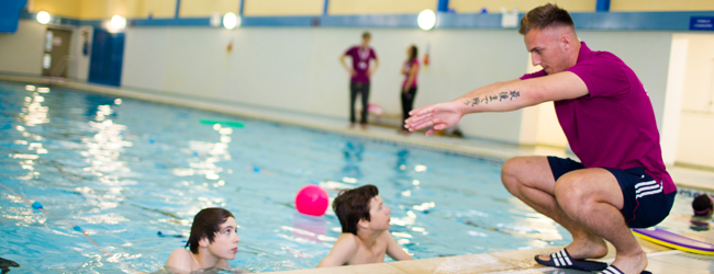 Schwimmunterricht im Pool bei einer Sprachreise für Schüler in Bath In einer Schwimmhalle zeigt ein Lehrer zwei Jungen im Schwimmbecken Schwimmübungen