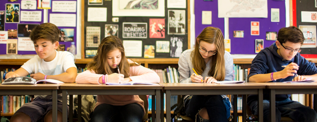 Konzentriertes Arbeiten bei einer Sprachreise für Schüler in Bath Vier Schüler sitzen konzentriert im Klassenzimmer und schreiben bei einer Sprachreise in Bath