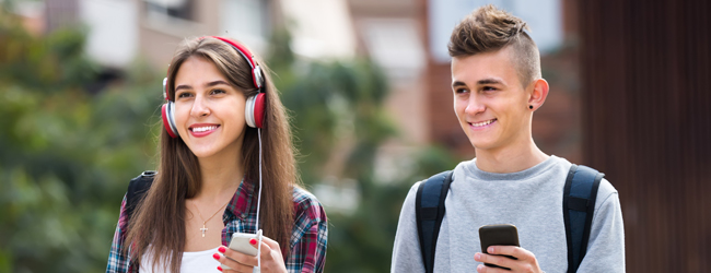 Zwei Schüler mit Handy und roten Kopfhörern unterwegs durch London bei einer Schülersprachreise