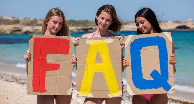 FAQ Sprachreisen - wichtige Fragen und Antworten Sprachreisen Malta St. Julians für Schüler Drei Mädchen halten Pappschilder in die Höhe mit den Buchstaben F A Q mit Hintergrund Meer