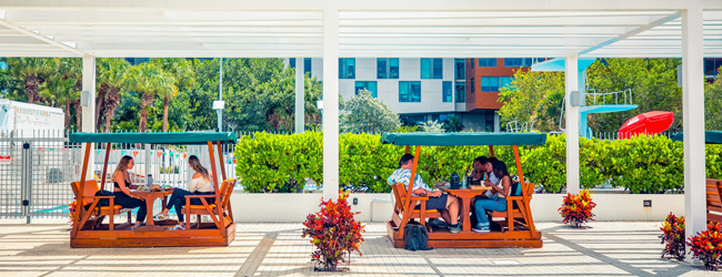 Pause auf dem Unicampus bei einer Sprachreise in Miami Schüler sitzen in kleinen orangnen Loungebänken mit Dach auf dem Universitätsgelände in Miami