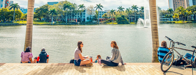 Pause am See vor der Universität von Miami bei einer Schülersprachreise Zwei Mädchen sitzen am See vor der Universität in Miami mit Palmen