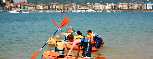 Kinder paddeln mit Booten im Meer vor der Küste San Sebastians bei einer Schülersprachreise
