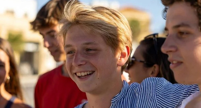 Ein blonder Junge lächelt und umarmt einen anderen Jungen